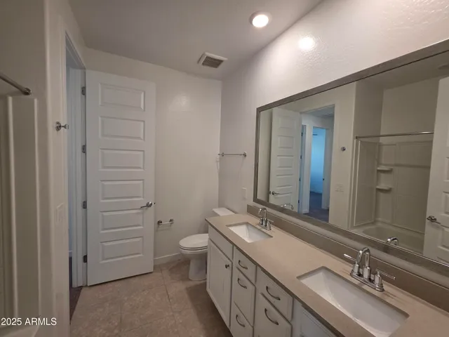 a bathroom with a double vanity sink a toilet and mirror