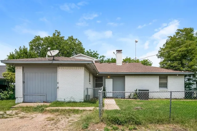 a view of a yard in front of a house with plants and large tree