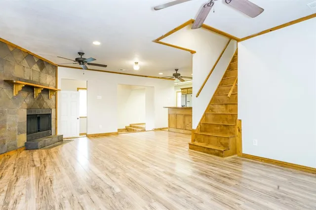 a view of an empty room with wooden floor and a fireplace