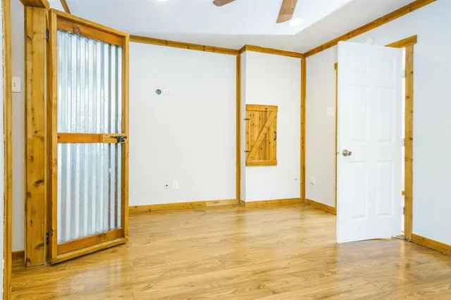 a view of an empty room with wooden floor and a window