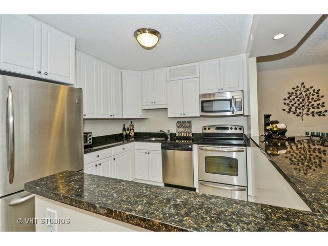 10 East Ontario Street, Unit 1109 Chicago, IL 60611 - Photo 3 of 11 a kitchen with granite countertop a stove a sink and a refrigerator
