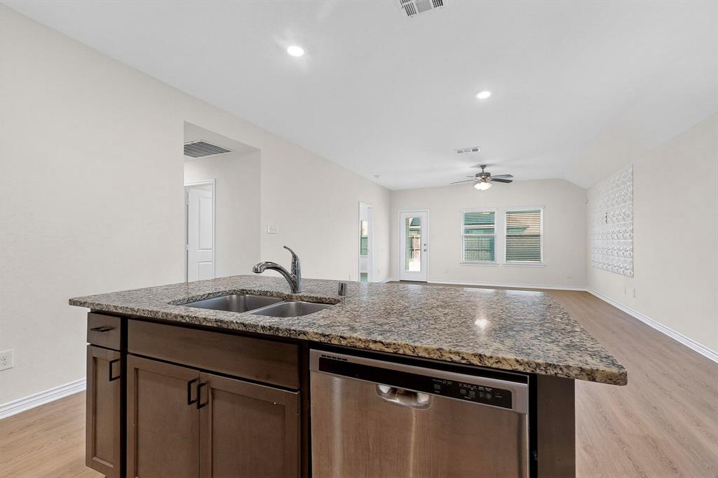 408 Rawhide Way Princeton, TX 75407 - Photo 12 of 36 a kitchen with granite countertop kitchen island a sink appliances and a counter space