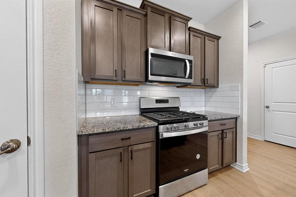 408 Rawhide Way Princeton, TX 75407 - Photo 13 of 36 a kitchen with granite countertop cabinets stainless steel appliances and wooden floor