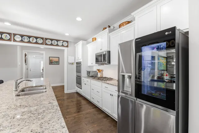 a large kitchen with stainless steel appliances granite countertop a refrigerator and a sink