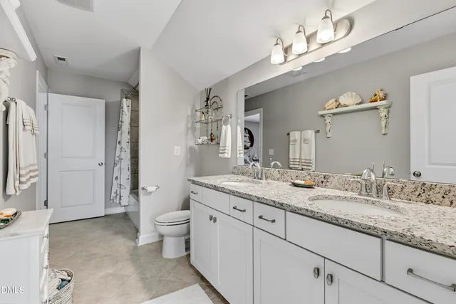 a bathroom with a granite countertop double vanity sink mirror and toilet