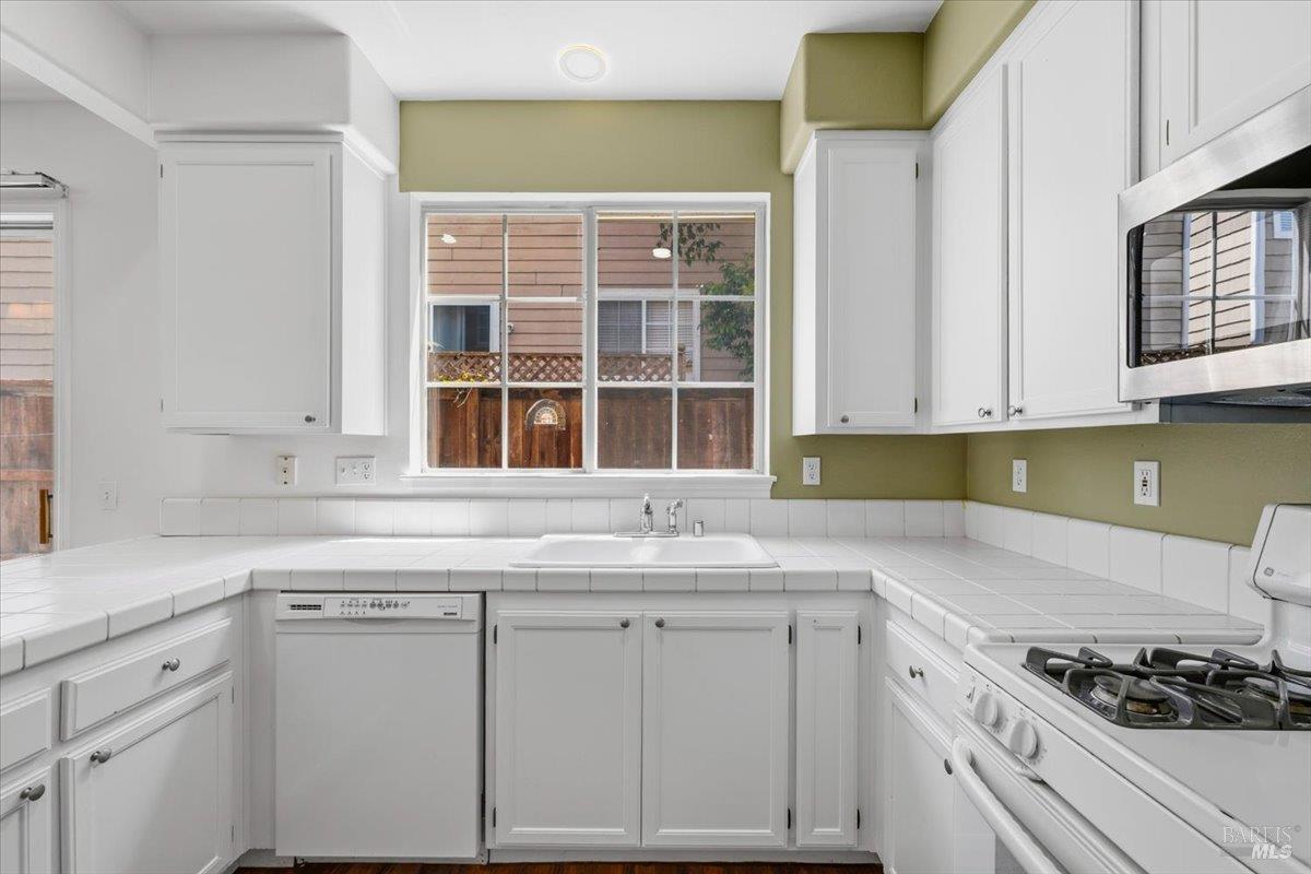1028 Addison Circle Petaluma, CA 94952 - Photo 18 of 60 a kitchen with white cabinets and appliances