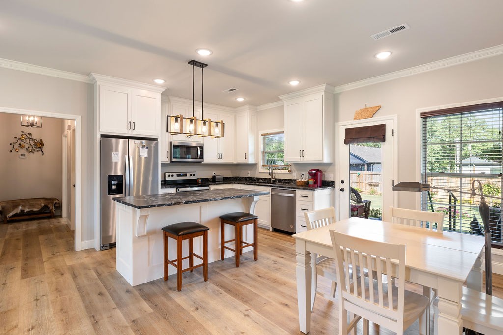 411 Bumpas Road Lawrenceburg, TN 38464 - Photo 12 of 30 a kitchen with stainless steel appliances kitchen island granite countertop a refrigerator a stove a sink a dining table and chairs with wooden floor