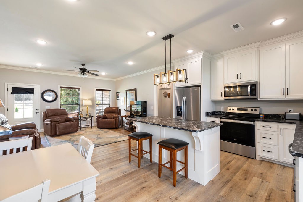 411 Bumpas Road Lawrenceburg, TN 38464 - Photo 9 of 30 a large kitchen with granite countertop a stove a sink a dining table and chairs with wooden floor