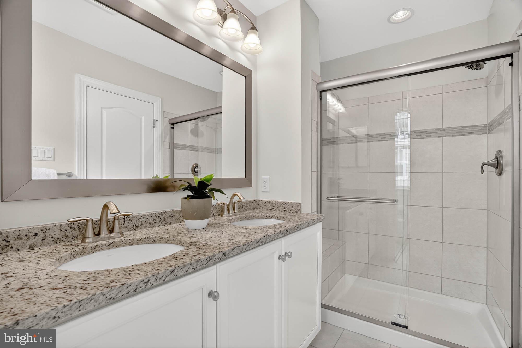 606 James Walker Place Annapolis, MD 21401 - Photo 30 of 52 a bathroom with a granite countertop sink a mirror and a shower