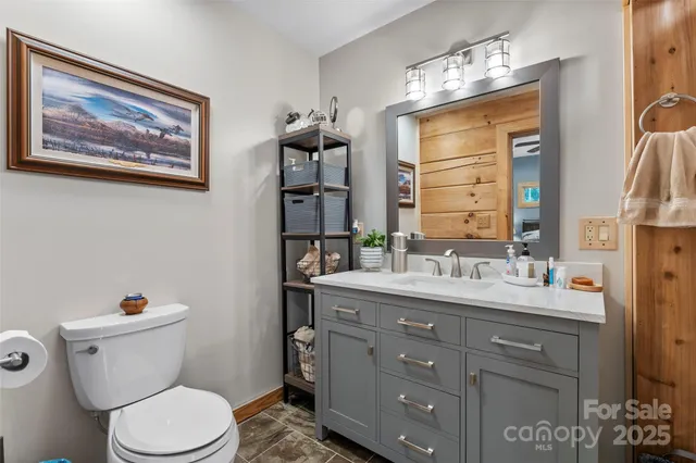 a bathroom with a granite countertop toilet a sink and a large mirror