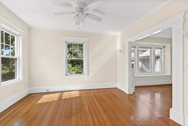 a view of an empty room with wooden floor and window