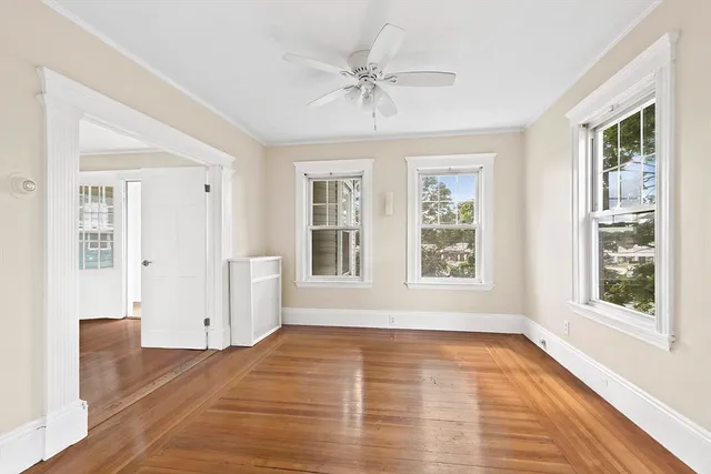 a view of an empty room with a window and wooden floor