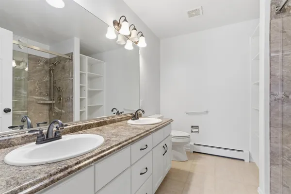 a bathroom with a granite countertop sink a toilet a mirror and shower