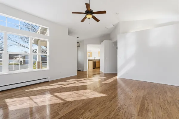 a view of an empty room with window and wooden floor