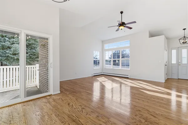 a view of an empty room with wooden floor fireplace and a window