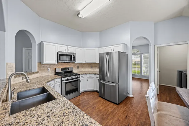 a kitchen with granite countertop a refrigerator and a stove top oven
