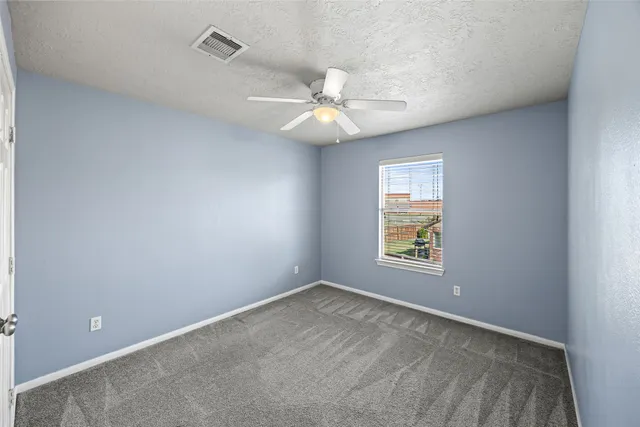 an empty room with a window and a fan