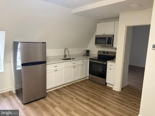 a kitchen with a sink a refrigerator and white cabinets