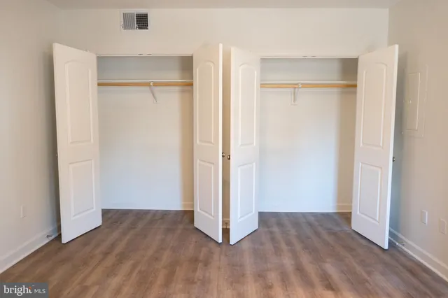 a view of an empty room with wooden floor & closet