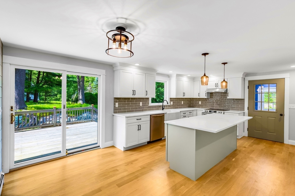 39 Middle Road, Unit A Newbury, MA 01951 - Photo 24 of 40 a large kitchen with a stove a sink dishwasher and white cabinets with wooden floor next to windows