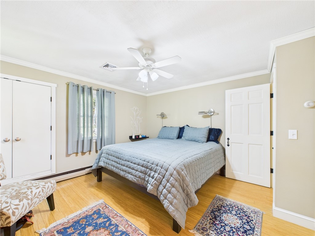 95 Mail Road Exeter, RI 02822 - Photo 19 of 33 Large, serene primary suite has soothing spa-like feel, continues the bamboo flooring and has 2 closets...the double doors to the left lead to the add-on walk-in. Note the beautiful, solid 6 panel entry doors to bedrooms & baths and the crown molding!