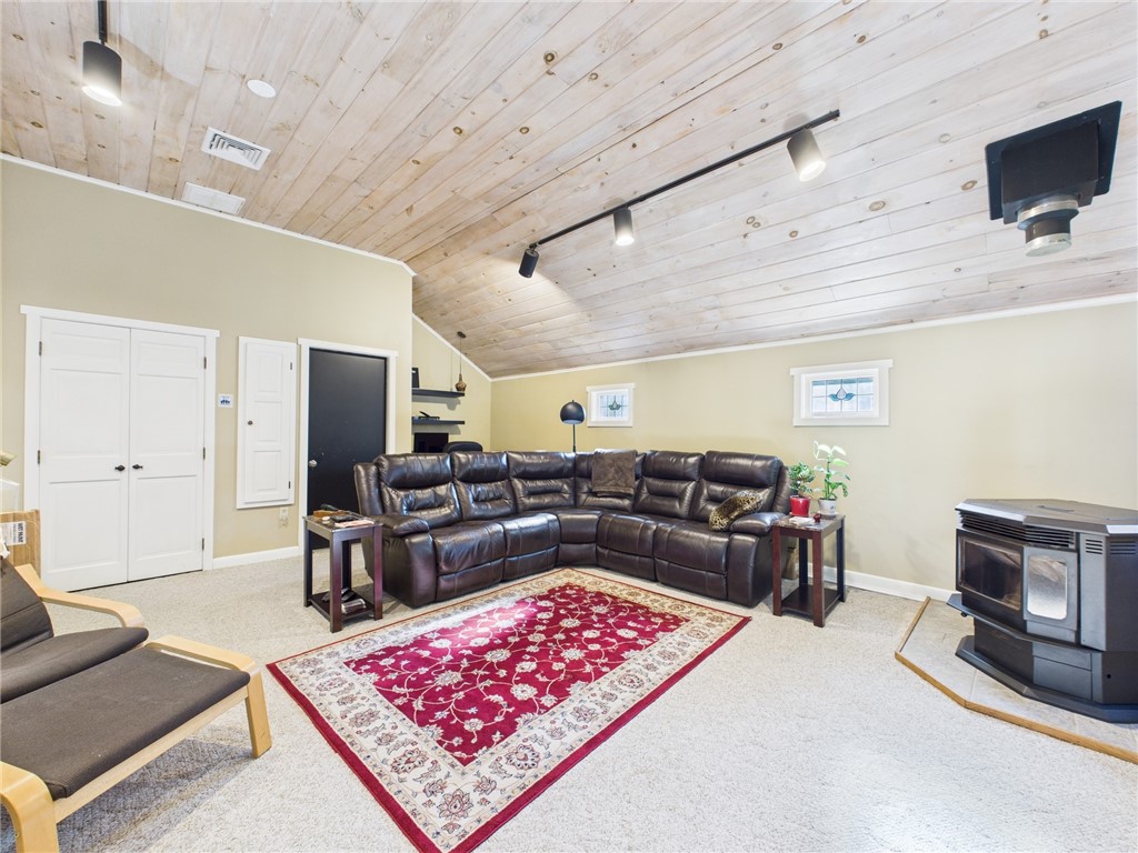 95 Mail Road Exeter, RI 02822 - Photo 24 of 33 The sumptuous, carpeted 380sf family room w/its alluring vaulted white pine ceiling is the perfect haven for evening relaxation with friends and family to watch favorite sporting events. The light tones of the room add to its comfort and appeal, coupled w/the natural light from the massive double hung window topped w/a grand arched brow pane w/an historic backstory. The double doors lead to a 1st floor laundry room! The black door leads to the garage.