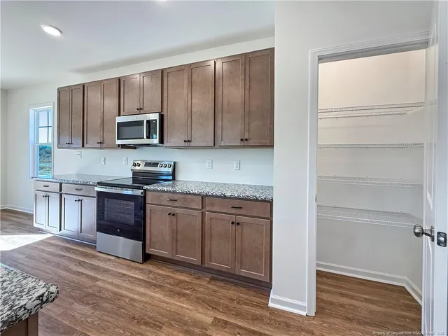 a kitchen with granite countertop a refrigerator stove and microwave