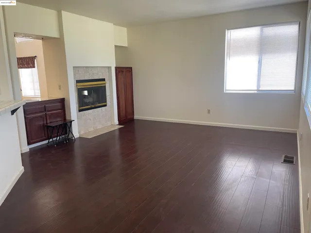 an empty room with wooden floor fireplace and windows