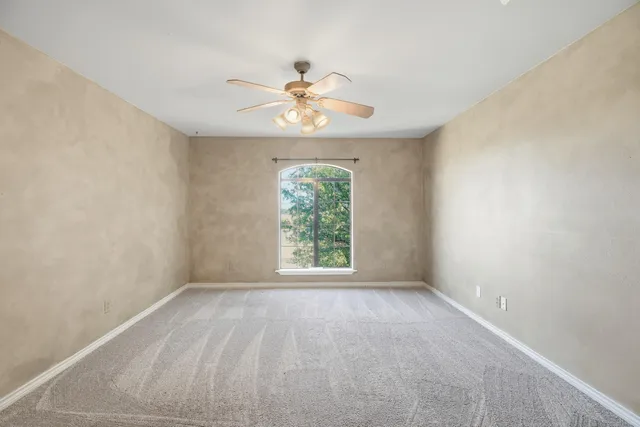 a view of an empty room with wooden floor a fireplace and a ceiling fan