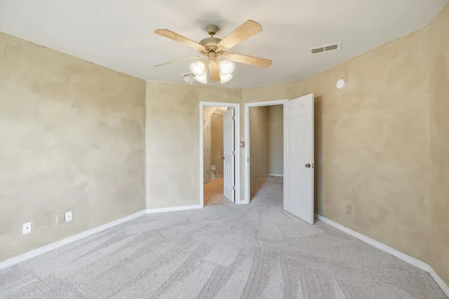 a view of an empty room with a fireplace and a chandelier fan