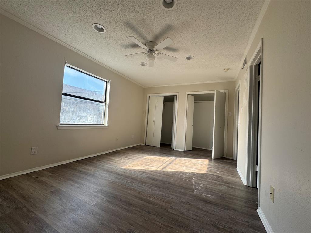 1421 South 12th Street, Unit 107 Waco, TX 76706 - Photo 12 of 25 an empty room with wooden floor chandelier fan and windows