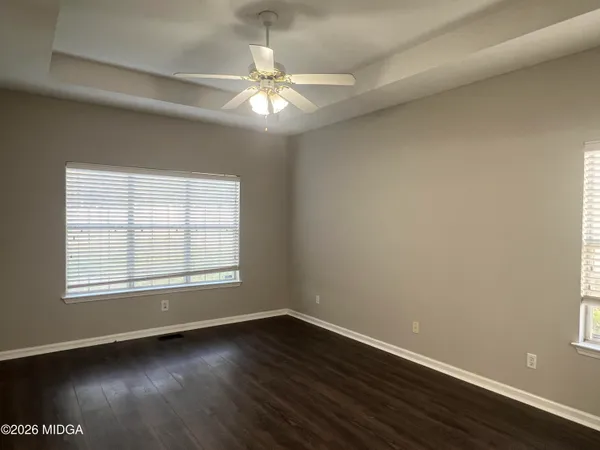 an empty room with wooden floor and windows