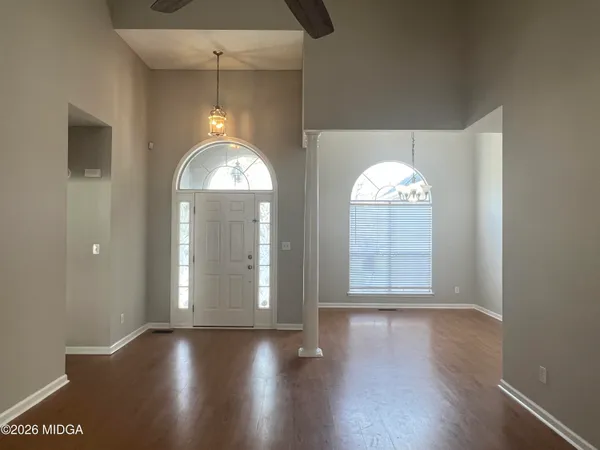 an empty room with wooden floor chandelier and glass door
