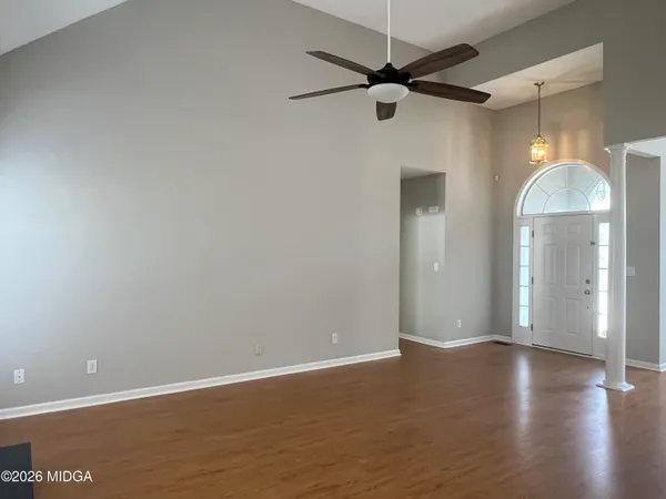 an empty room with wooden floor fan and windows