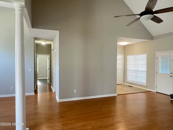 a view of an empty room with window and wooden floor