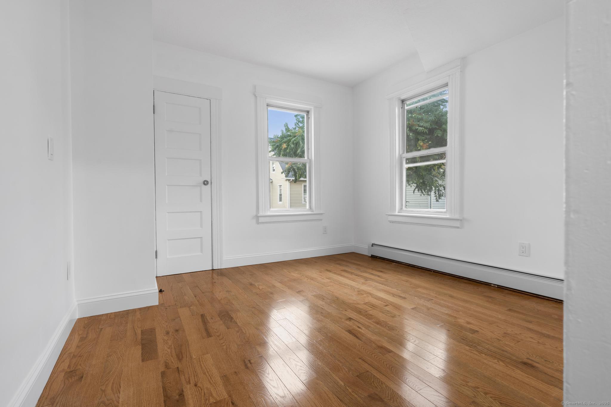 565 Carroll Avenue, Unit 1 Bridgeport, CT 06607 - Photo 15 of 22 an empty room with wooden floor and windows