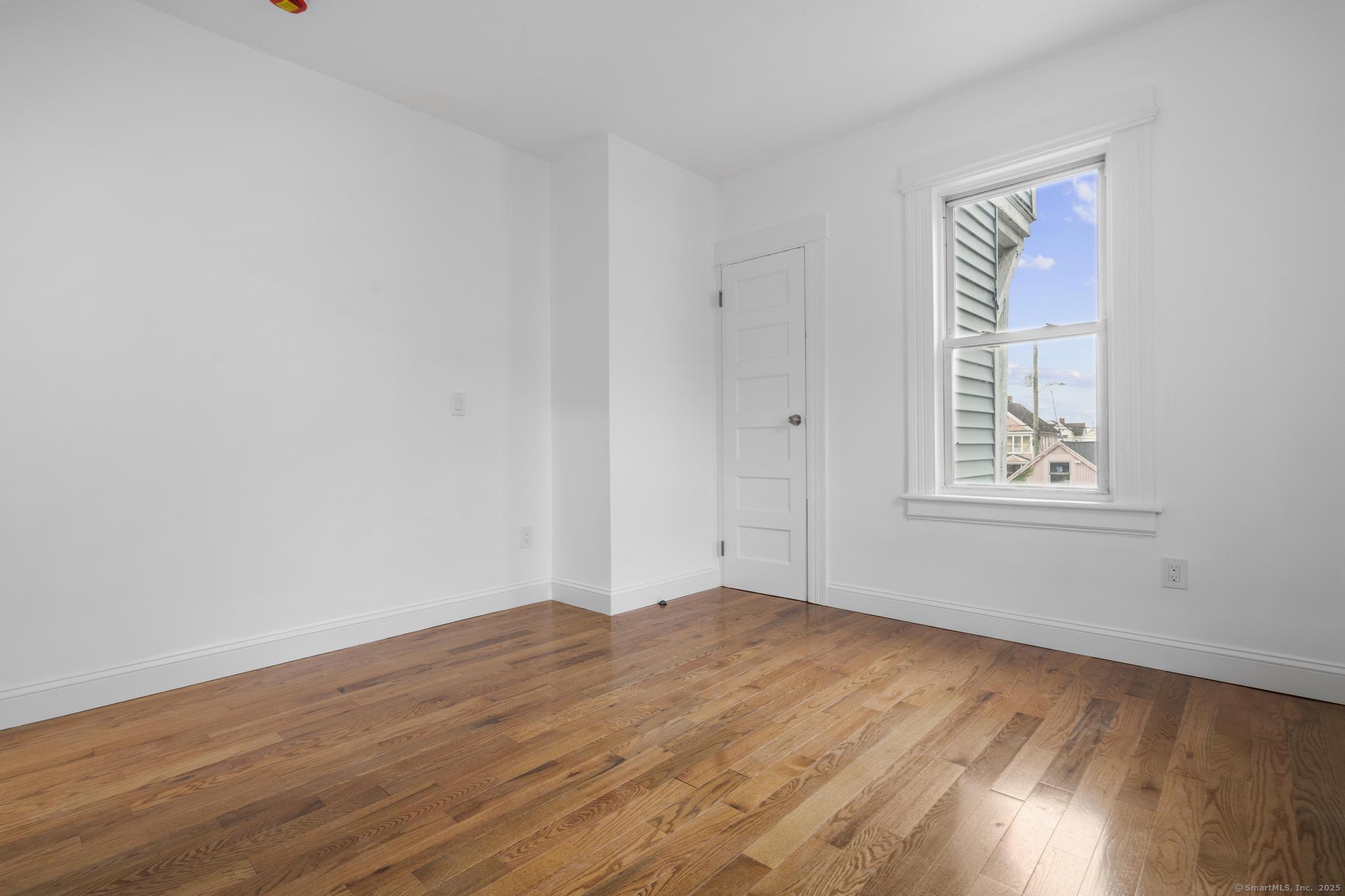 565 Carroll Avenue, Unit 1 Bridgeport, CT 06607 - Photo 16 of 22 a view of an empty room with wooden floor and a window