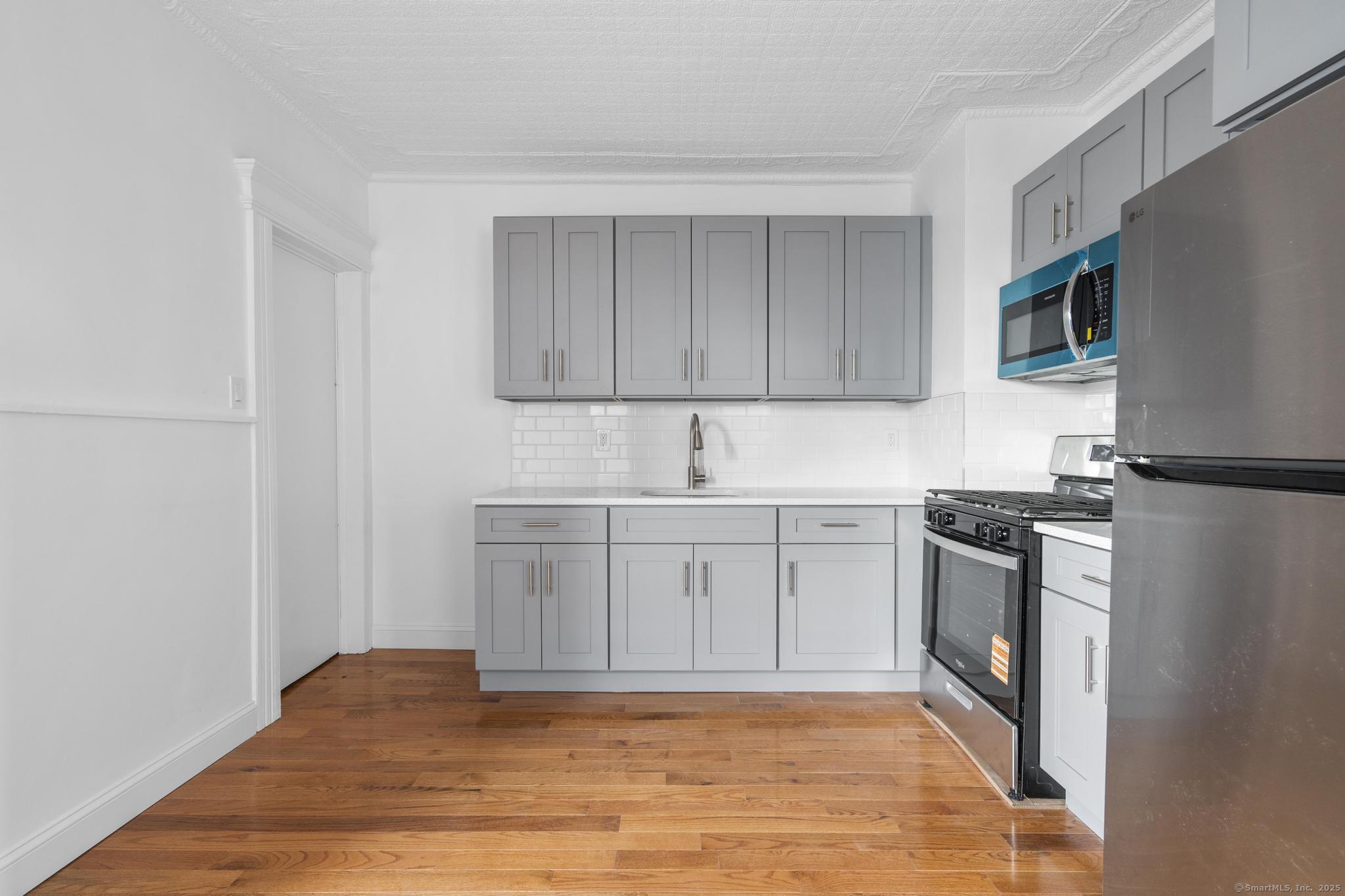 565 Carroll Avenue, Unit 1 Bridgeport, CT 06607 - Photo 20 of 22 a kitchen with stainless steel appliances granite countertop a sink stove and refrigerator