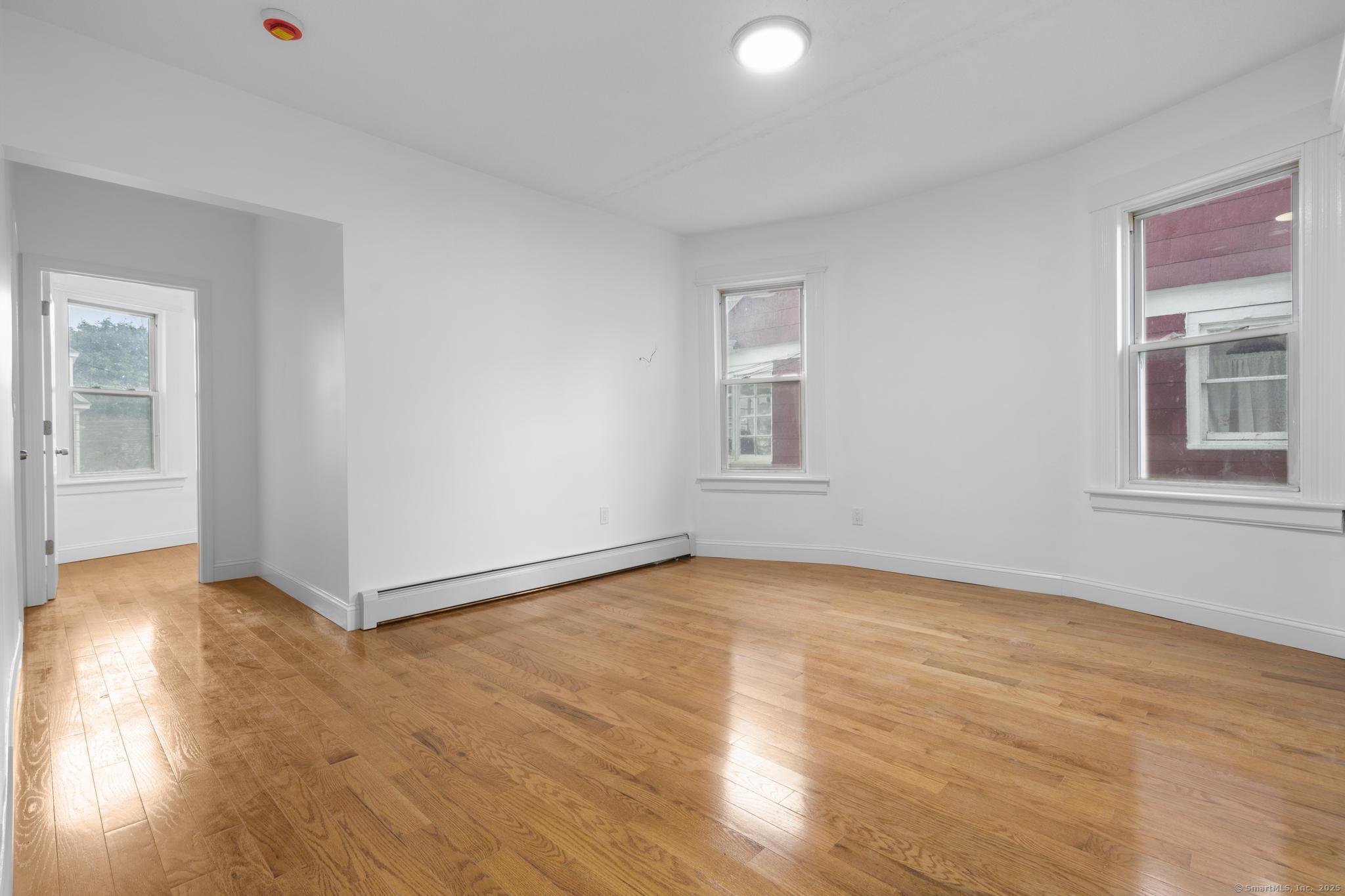 565 Carroll Avenue, Unit 1 Bridgeport, CT 06607 - Photo 5 of 22 an empty room with wooden floor and windows