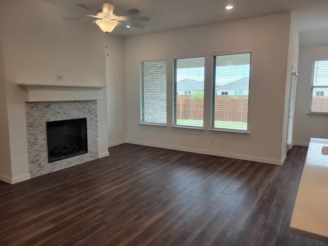 a view of an empty room with wooden floor fireplace and a window