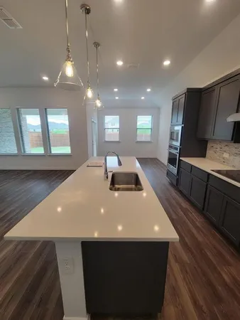 a large kitchen with stainless steel appliances a large counter top a stove and a sink