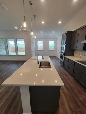 a large kitchen with stainless steel appliances a large counter top a stove and a sink