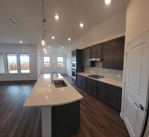 a kitchen with kitchen island a sink appliances and cabinets