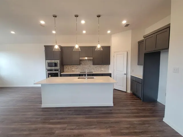 a view living room with stainless steel appliances kitchen island granite countertop a stove a refrigerator a sink and a oven with wooden floor