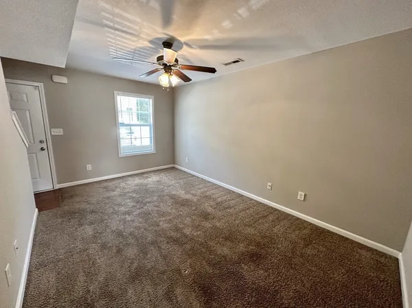an empty room with windows and fan