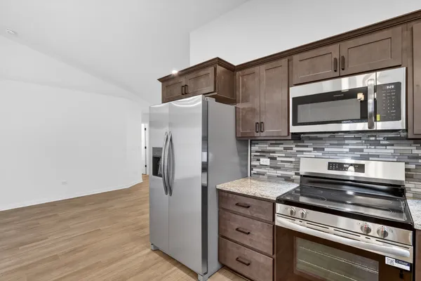 a kitchen with granite countertop cabinets stainless steel appliances and wooden floor