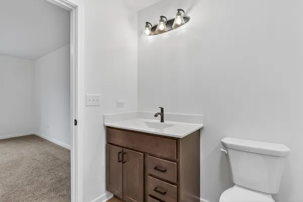 a bathroom with a toilet sink vanity and mirror