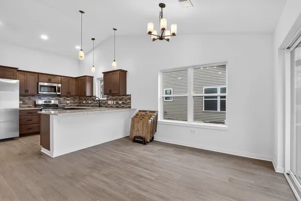 a kitchen with stainless steel appliances kitchen island granite countertop a dishwasher a stove a refrigerator and white cabinets with wooden floor