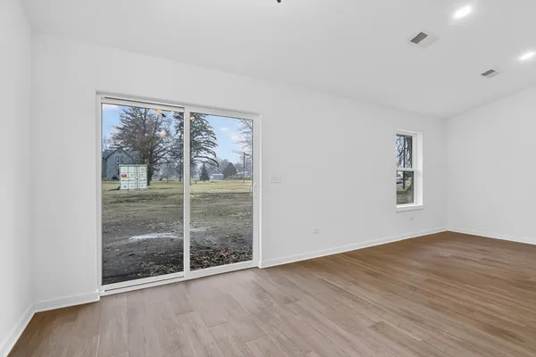 an empty room with wooden floor and windows