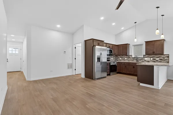 a kitchen with stainless steel appliances a refrigerator and a wooden floor